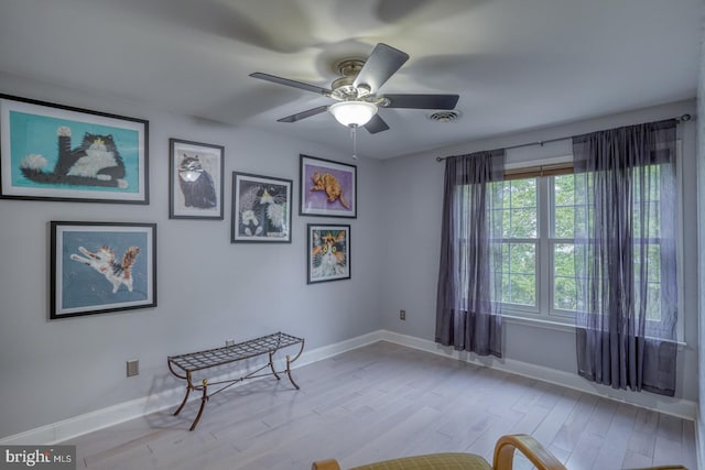 living area featuring wood finished floors, ceiling fan, and baseboards
