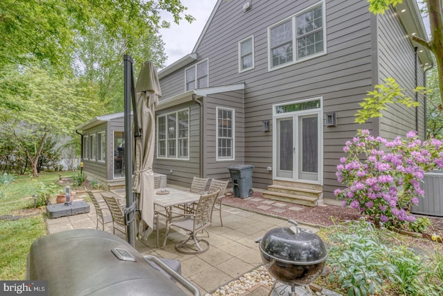 rear view of property with entry steps, a patio area, outdoor dining space, and central air condition unit