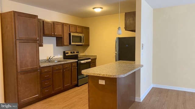 kitchen with a sink, light wood-style flooring, appliances with stainless steel finishes, and a peninsula