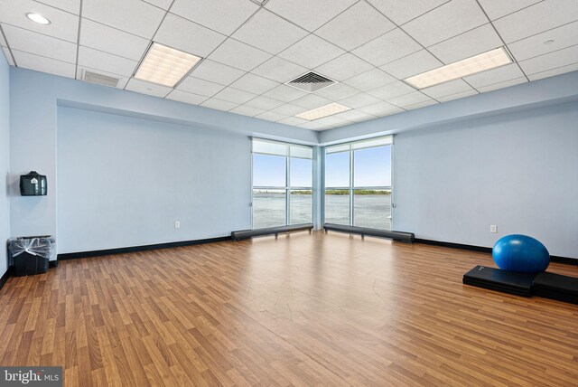exercise room featuring baseboards, a drop ceiling, wood finished floors, and visible vents