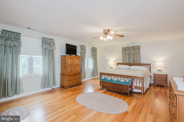 bedroom with baseboards, a ceiling fan, light wood finished floors, and visible vents