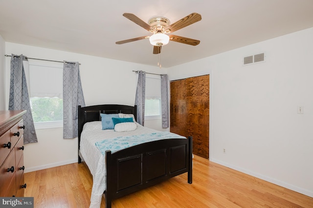 bedroom with visible vents, light wood finished floors, baseboards, and a ceiling fan