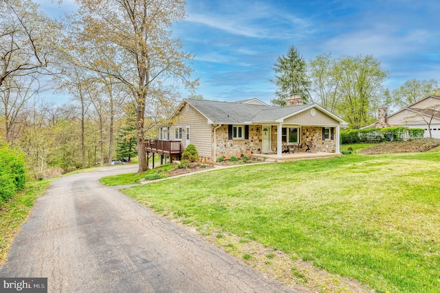 single story home with a porch, stone siding, a front lawn, and driveway
