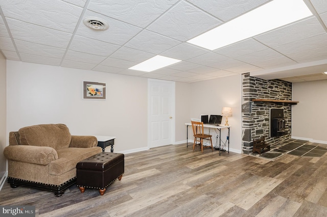 living area featuring baseboards, wood finished floors, visible vents, and a fireplace