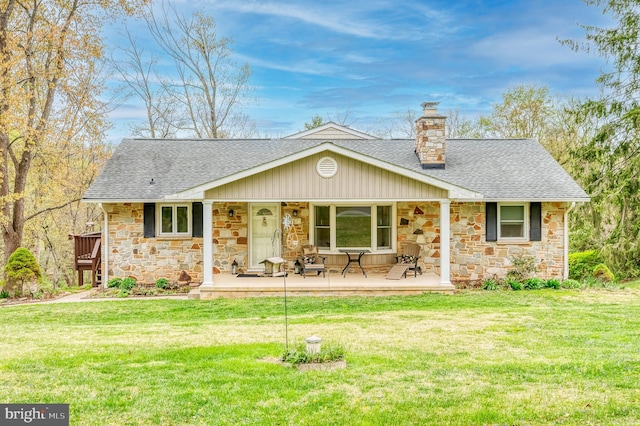 view of front of home with a front lawn, roof with shingles, stone siding, and a chimney
