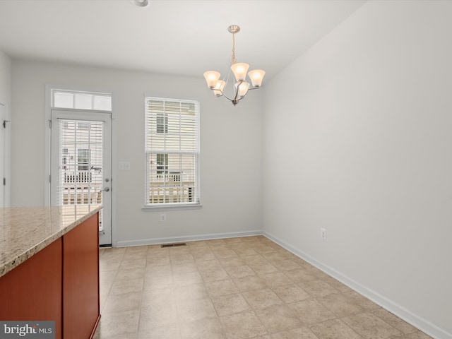 unfurnished dining area with baseboards, visible vents, and an inviting chandelier