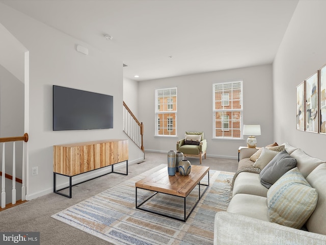 living room featuring baseboards, carpet floors, and stairs