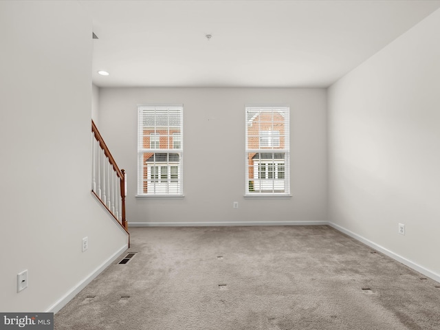 empty room with visible vents, baseboards, carpet floors, and stairway