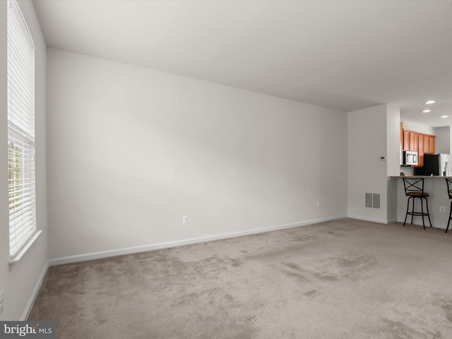 unfurnished living room with light colored carpet, baseboards, visible vents, and recessed lighting