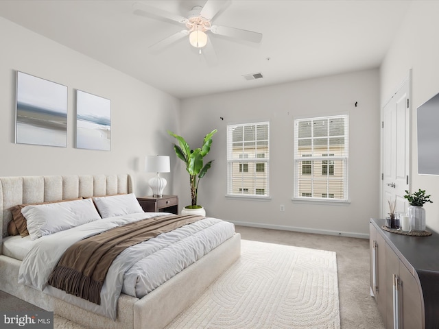 bedroom featuring baseboards, visible vents, light colored carpet, and ceiling fan