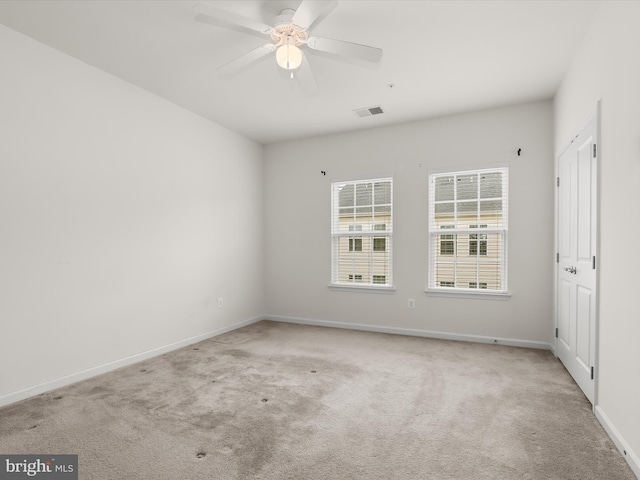 empty room with baseboards, visible vents, light colored carpet, and ceiling fan
