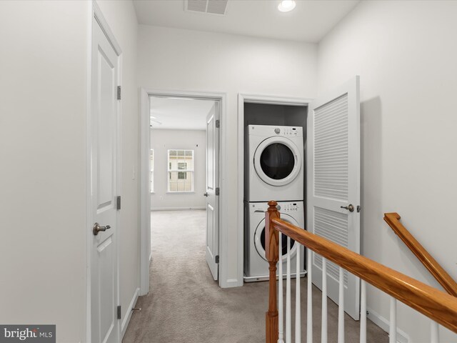 hallway with an upstairs landing, carpet floors, stacked washer / drying machine, baseboards, and visible vents