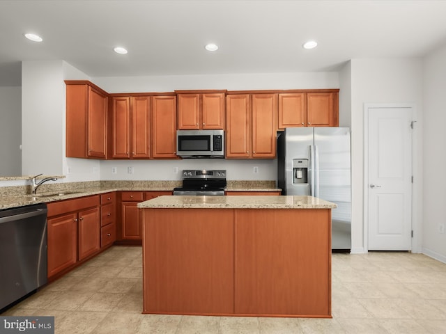 kitchen with stainless steel appliances, a center island, a sink, recessed lighting, and light stone countertops