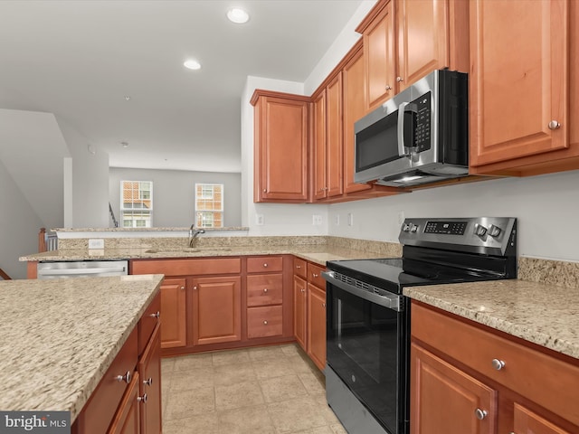 kitchen with light stone counters, brown cabinetry, stainless steel appliances, and a sink