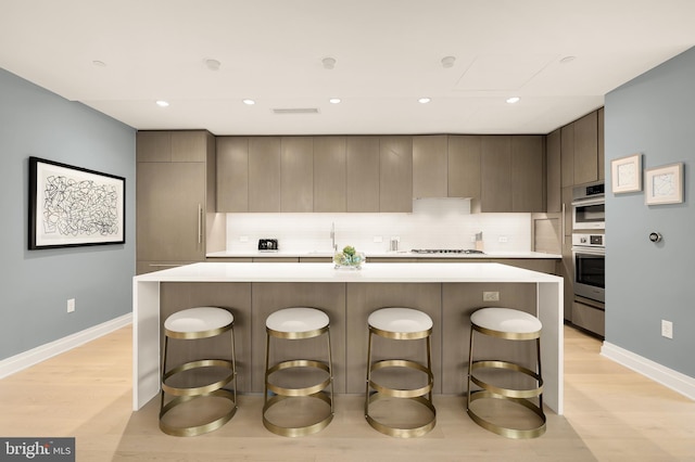 kitchen with wall oven, white gas cooktop, light wood finished floors, light countertops, and modern cabinets