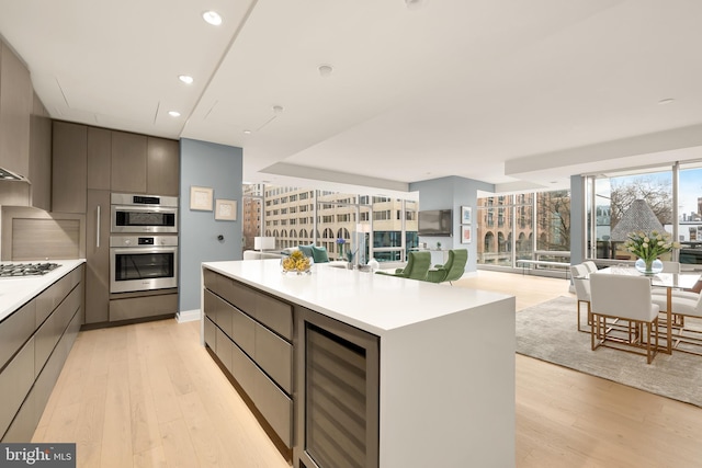 kitchen with wine cooler, light wood-style flooring, modern cabinets, a center island, and recessed lighting