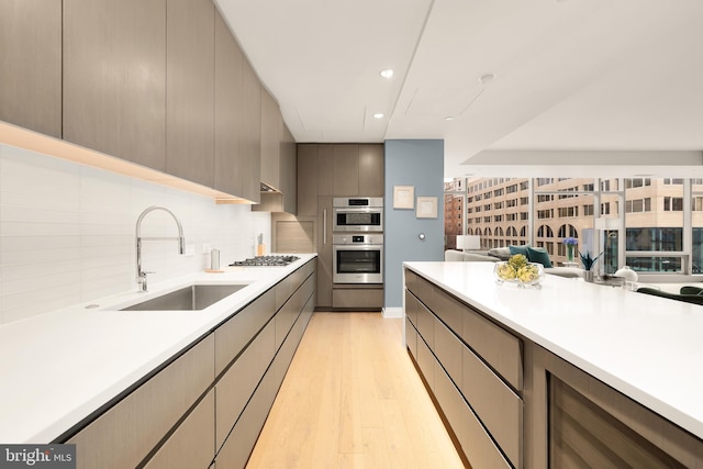 kitchen featuring a sink, light wood-style floors, stainless steel appliances, light countertops, and recessed lighting