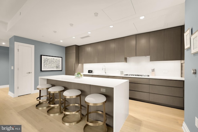 kitchen featuring light wood-style floors, a kitchen island, a kitchen bar, light countertops, and recessed lighting