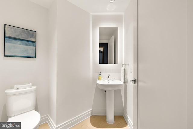 bathroom with toilet, wood finished floors, and baseboards