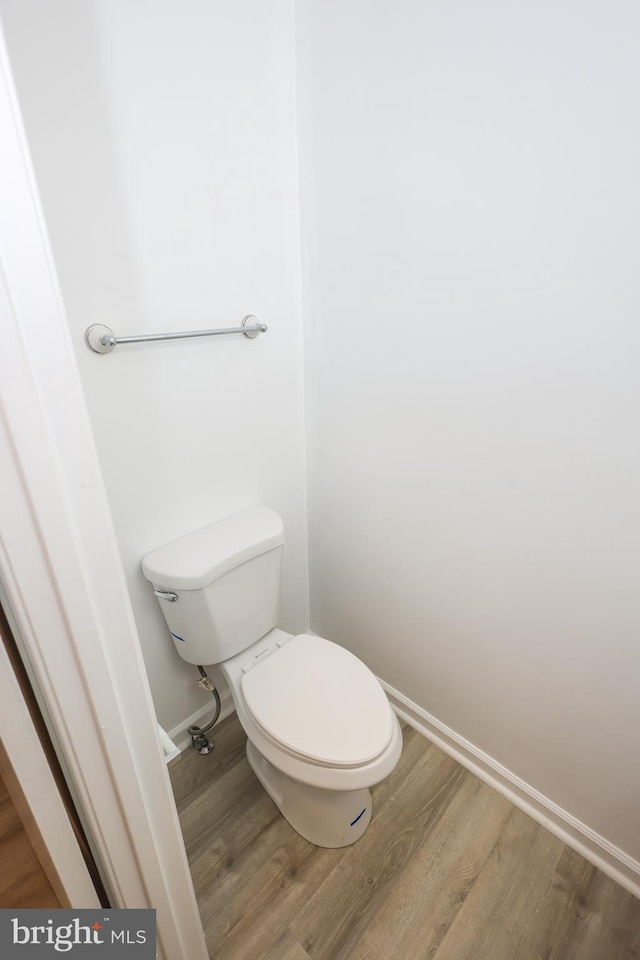 bathroom with toilet, baseboards, and wood finished floors