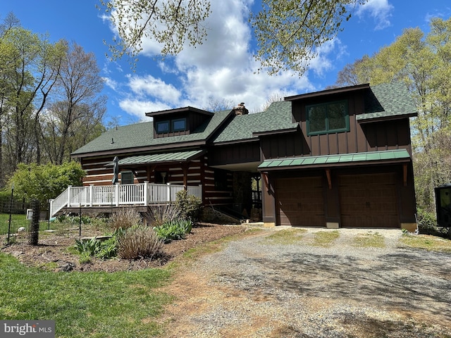 view of front of house featuring board and batten siding, driveway, a chimney, an attached garage, and a shingled roof
