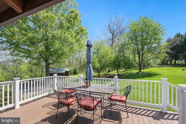 wooden deck with a lawn, outdoor dining space, and an outdoor structure