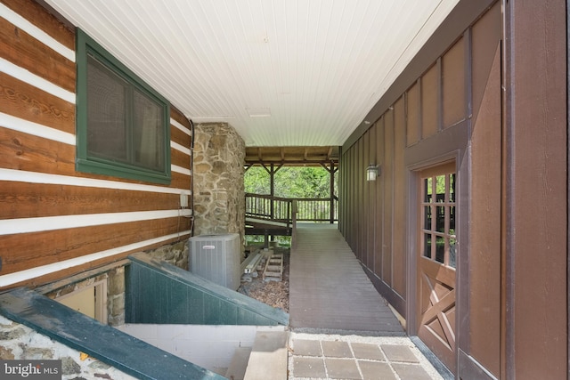 interior space with board and batten siding, central AC, and stone siding