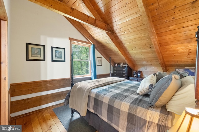 bedroom with wood-type flooring, lofted ceiling with beams, wooden ceiling, and a wainscoted wall