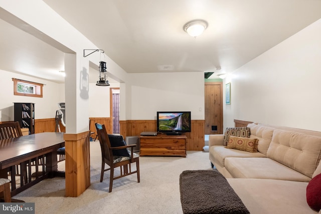 living room featuring wooden walls, wainscoting, and light colored carpet