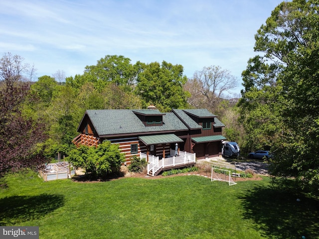 rear view of property featuring a garage, a yard, and log siding