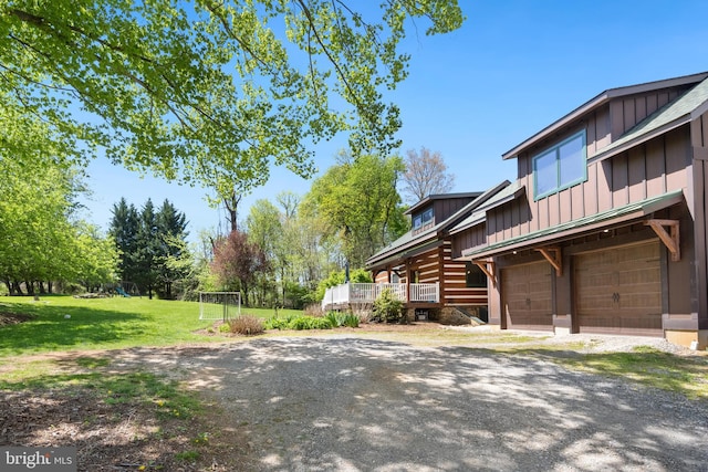 view of side of home featuring board and batten siding, a yard, driveway, and a garage