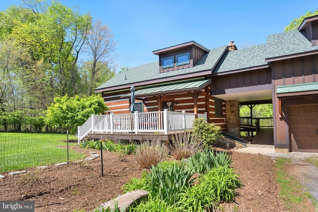 back of property featuring roof with shingles, a wooden deck, log exterior, and a lawn