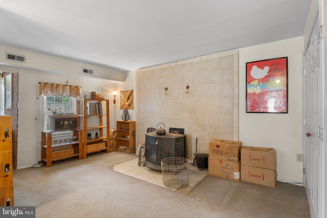 carpeted living area with a wood stove and visible vents