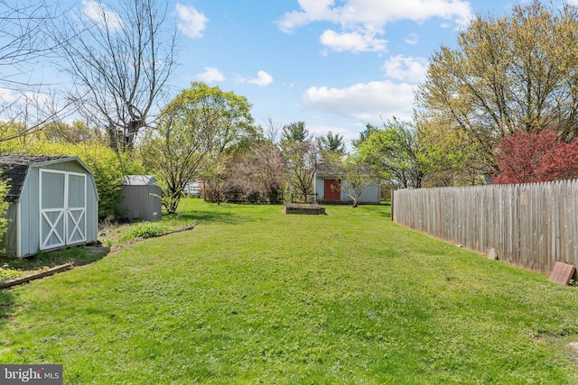 view of yard featuring fence, an outdoor structure, and a storage shed