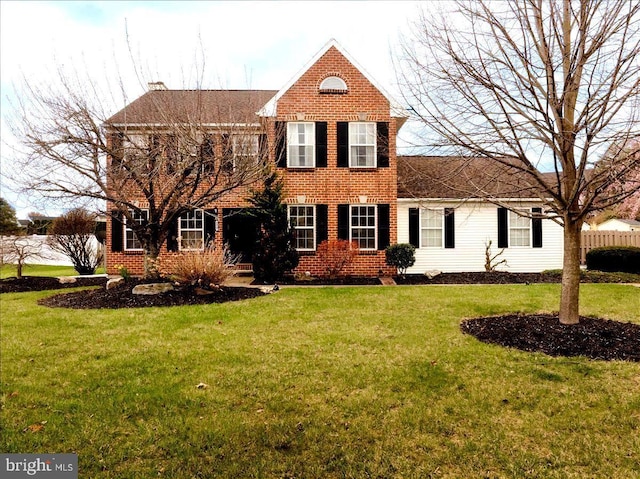 colonial-style house featuring brick siding and a front yard