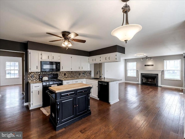 kitchen featuring ceiling fan, black appliances, a kitchen island, baseboards, and open floor plan