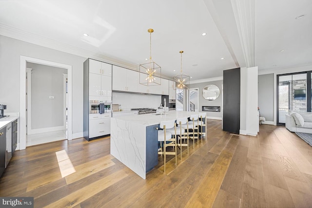 1109 Towlston Rd, Mclean, VA 22102 - kitchen featuring a large island with sink, baseboards, wood-type flooring, ornamental molding, and white cabinetry