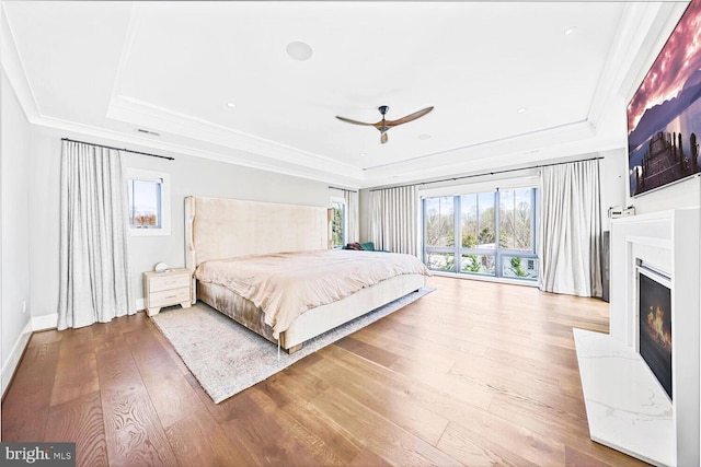 1109 Towlston Rd, Mclean, VA 22102 - bedroom featuring a warm lit fireplace, a tray ceiling, crown molding, and wood finished floors
