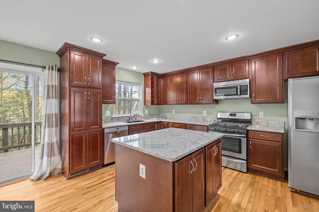 kitchen featuring light stone counters, light wood finished floors, appliances with stainless steel finishes, and a kitchen island