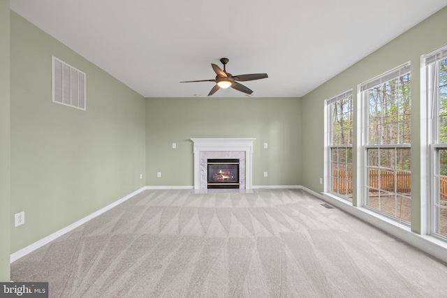 unfurnished living room featuring carpet flooring, baseboards, visible vents, and a high end fireplace