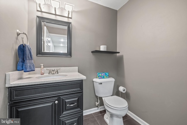 half bathroom with vanity, baseboards, tile patterned floors, and toilet