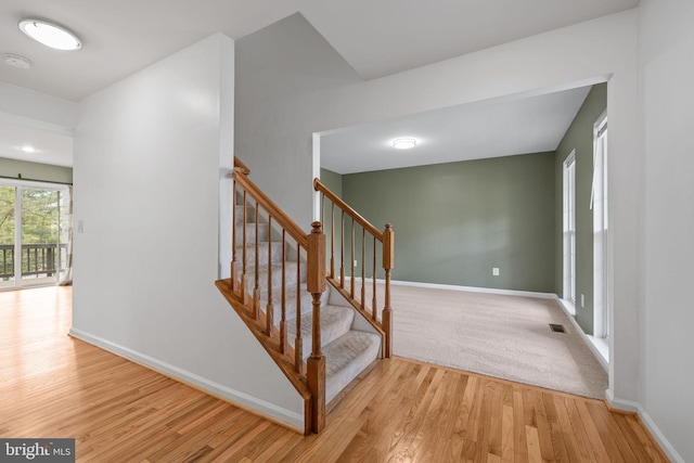 staircase featuring baseboards, wood finished floors, and visible vents