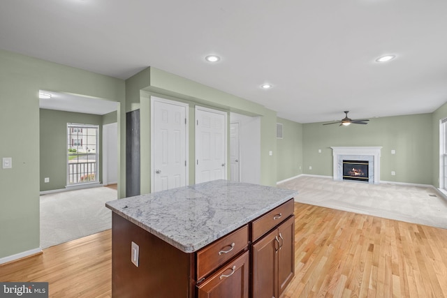 kitchen with a ceiling fan, baseboards, light colored carpet, and light wood finished floors