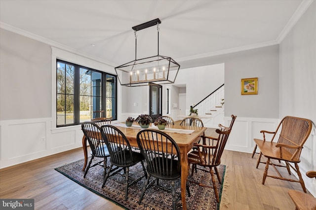 dining room with a wainscoted wall, crown molding, stairway, a chandelier, and wood finished floors