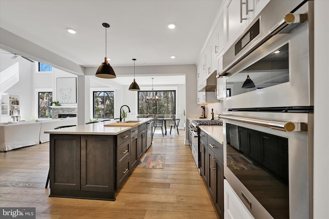 kitchen featuring light countertops, stainless steel appliances, white cabinets, dark brown cabinetry, and a fireplace