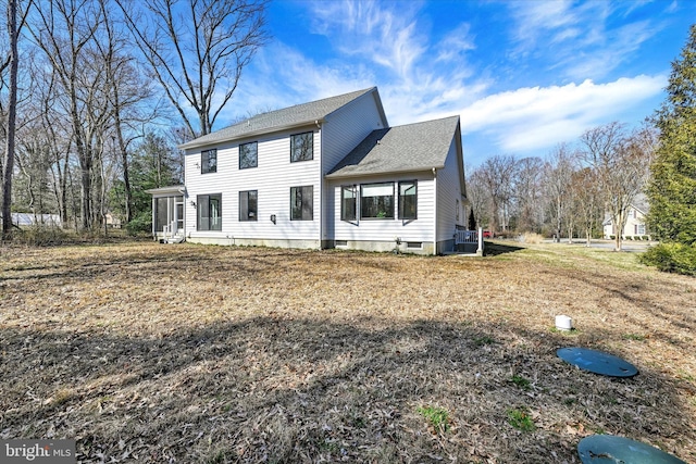 colonial home featuring central AC unit, a shingled roof, and a sunroom