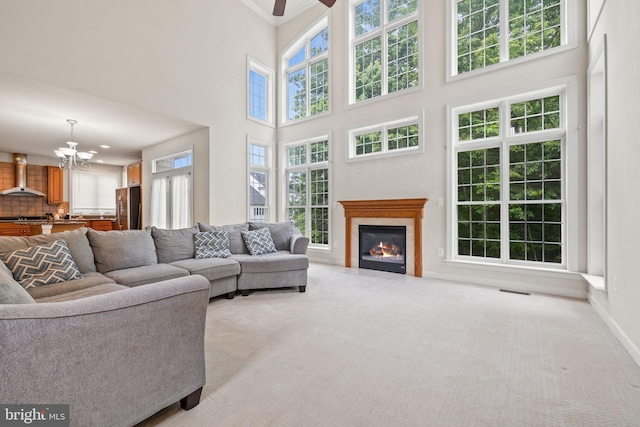 18547 Kerill Rd, Triangle, VA 22172 - living area with light colored carpet, a chandelier, a towering ceiling, a fireplace with flush hearth, and ceiling fan