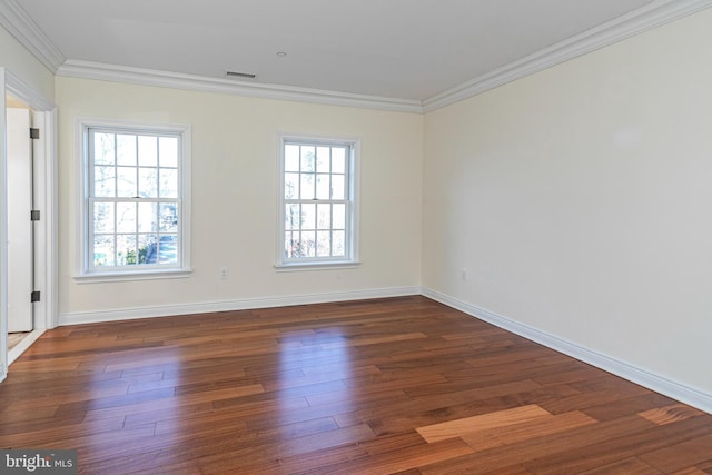 empty room with baseboards, visible vents, ornamental molding, and wood finished floors