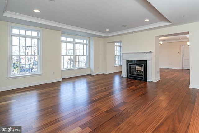 unfurnished living room with dark wood-style flooring, a tray ceiling, crown molding, and a wealth of natural light