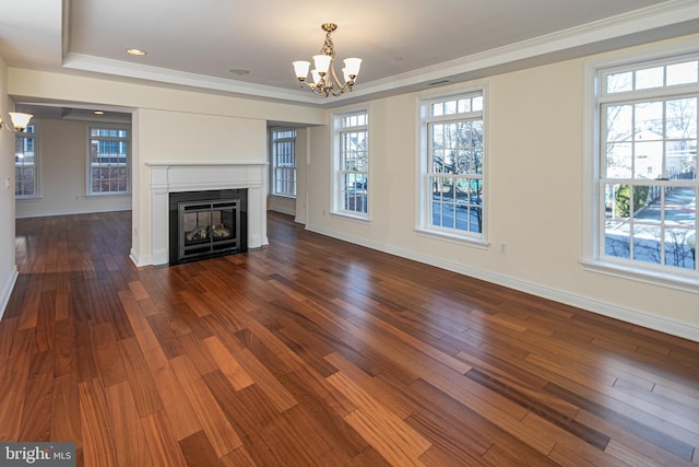 unfurnished living room featuring a wealth of natural light, wood finished floors, a glass covered fireplace, and a notable chandelier